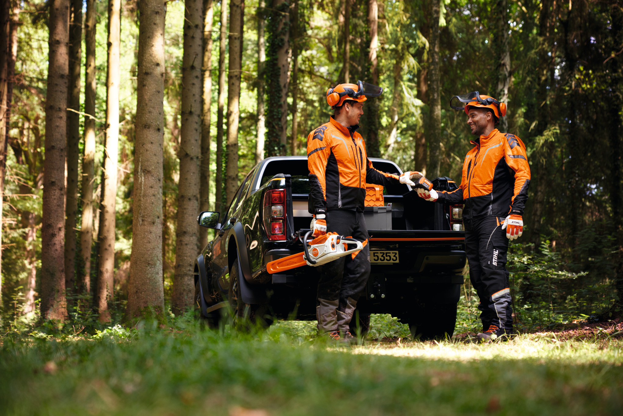 Des travailleurs forestiers debout dans une forêt, vêtus d'équipement de protection individuelle STIHL.