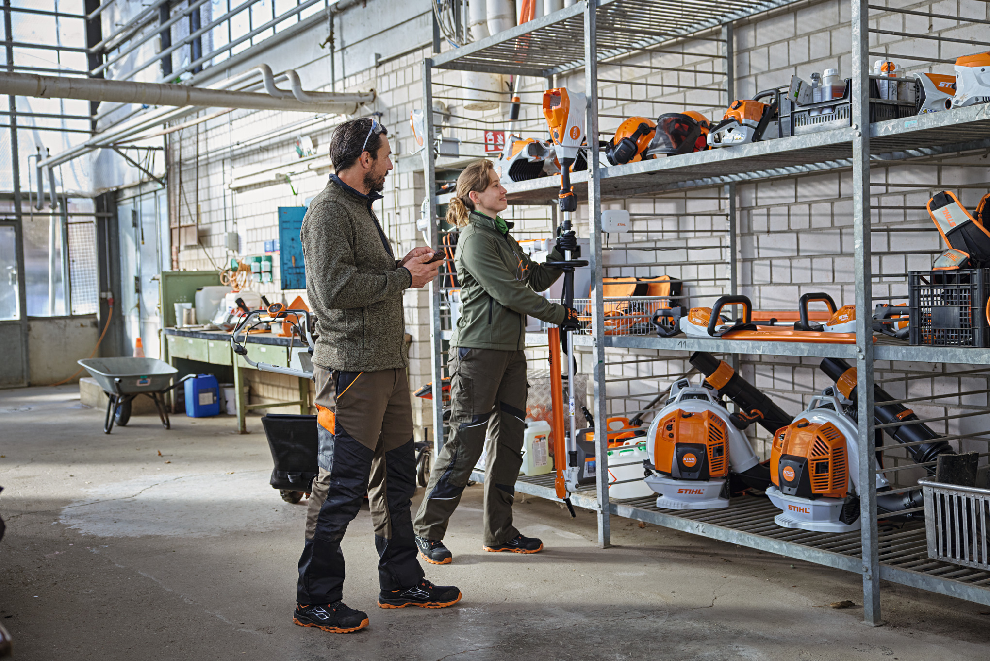 Les professionnels de l'aménagement paysager vérifient l'état des produits dans un entrepôt à l'aide de l'application STIHL connected.