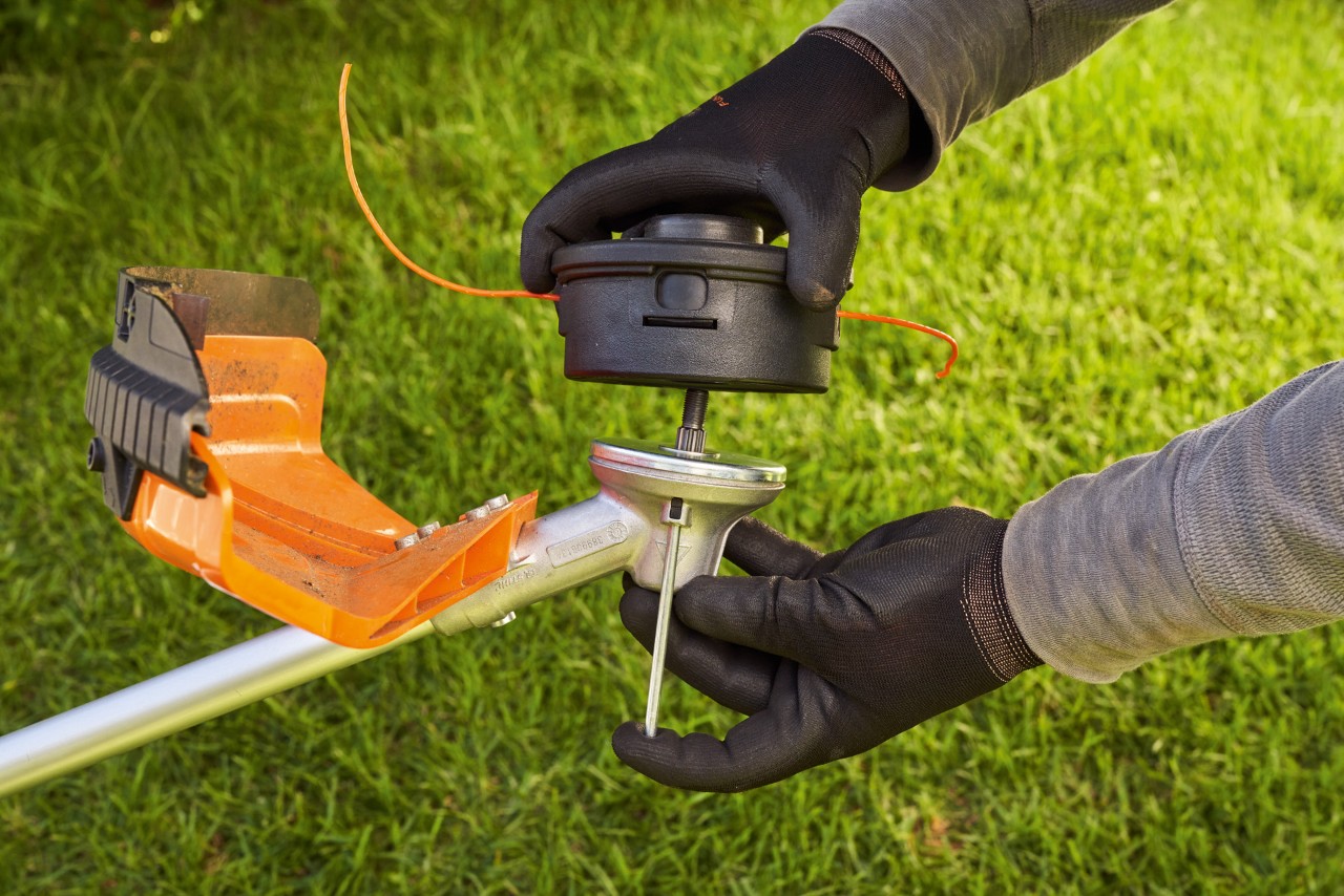A STIHL replacement grass trimmer head is rotated onto the tool