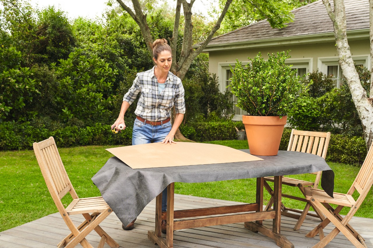 A woman laying out all the materials needed to trim a boxwood on a garden table 