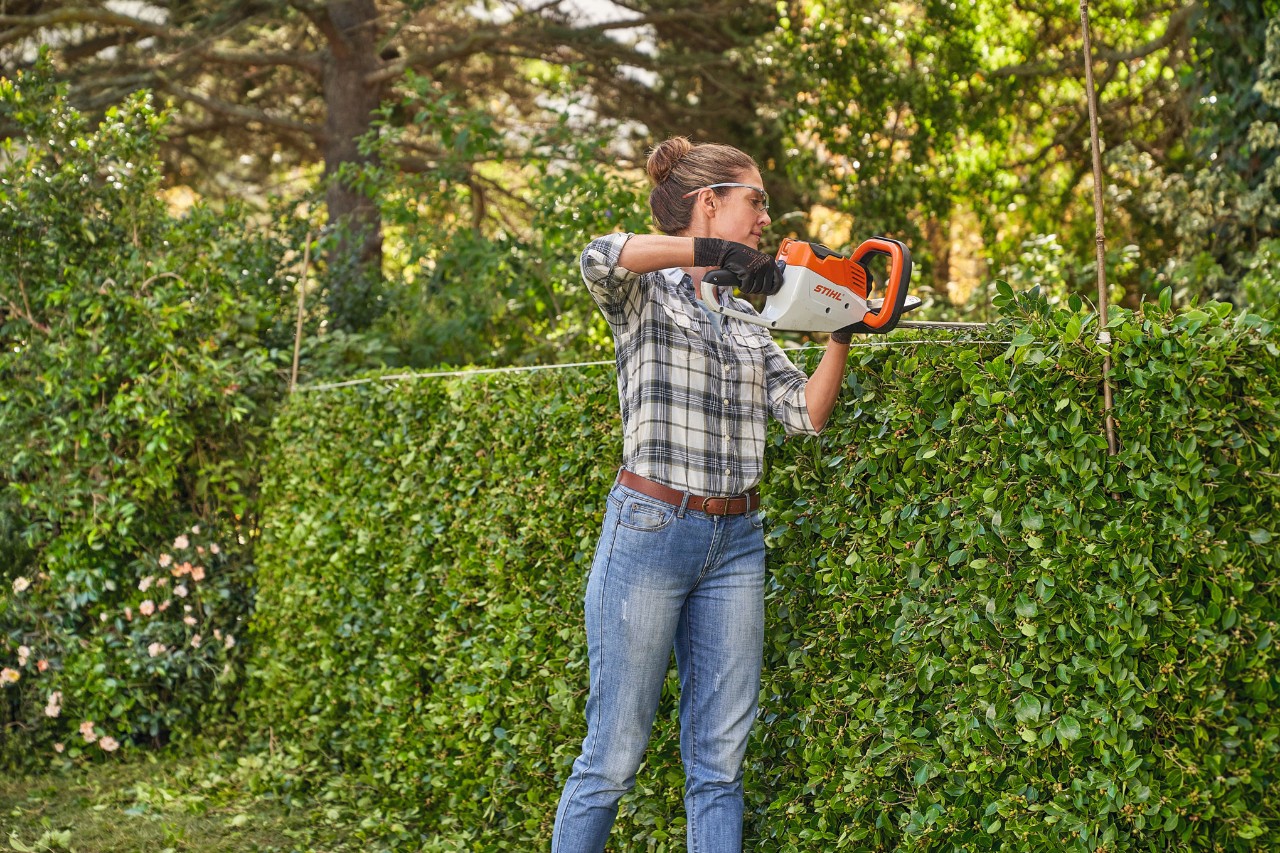 Une femme taille une haie avec le taille-haie à batterie STIHL HSA 45