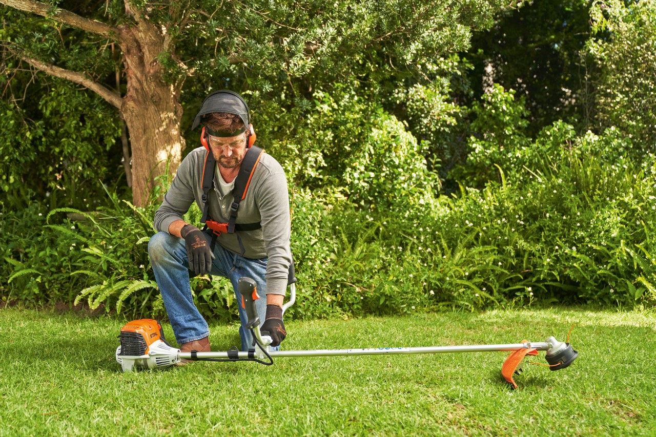 Un homme posant la débroussailleuse à essence STIHL&nbsp;FS&nbsp;91 au sol pour la démarrer