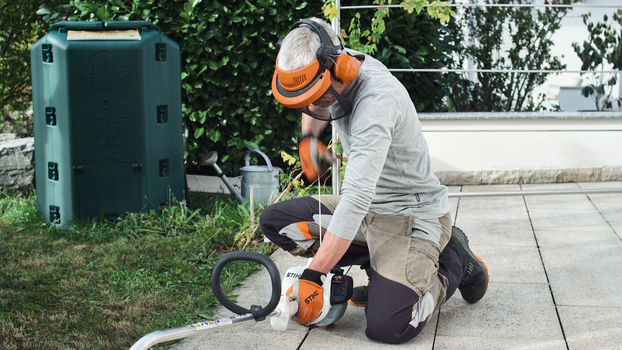 Une personne portant des vêtements de protection et tirant sur la corde de démarrage de la débroussailleuse à essence STIHL&nbsp;FS&nbsp;38