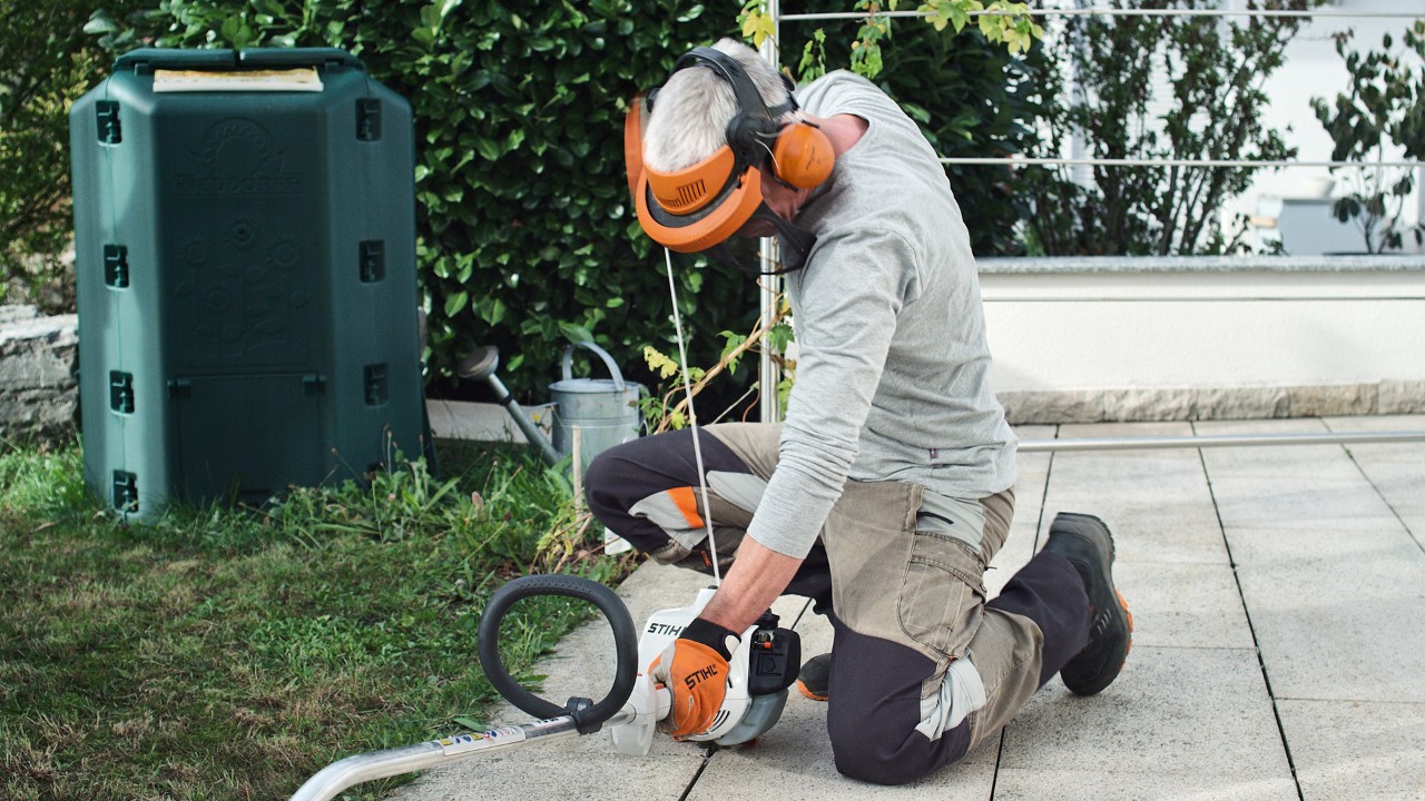 Une personne portant des vêtements de protection et tirant à nouveau sur la corde de démarrage de la débroussailleuse à essence STIHL&nbsp;FS&nbsp;38