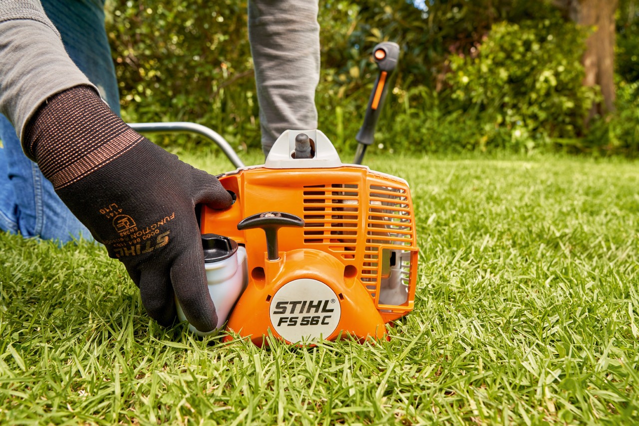 Un homme appuyant sur la pompe à carburant de la débroussailleuse à essence STIHL&nbsp;FS&nbsp;56 pour la démarrer
