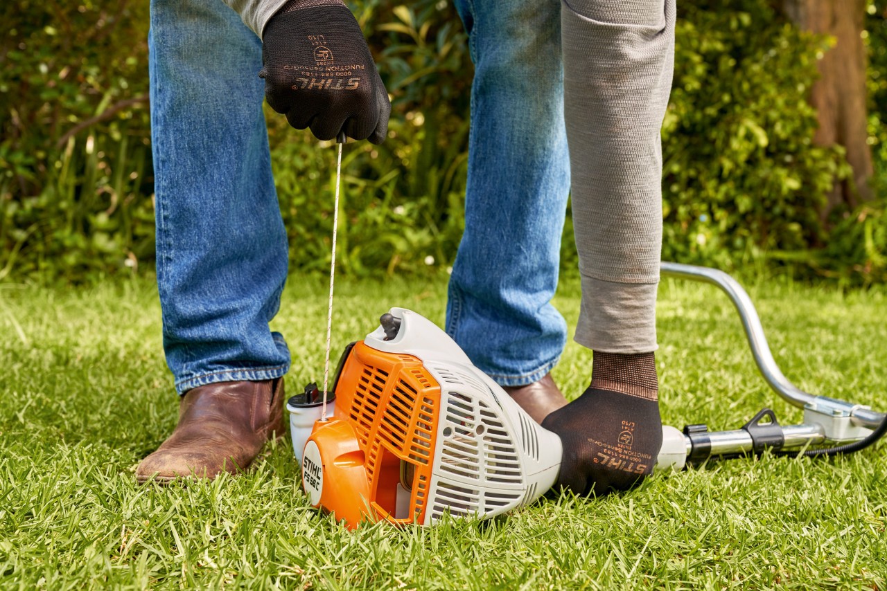 Un homme tirant sur le câble de démarrage de la débroussailleuse à essence STIHL&nbsp;FS&nbsp;56 