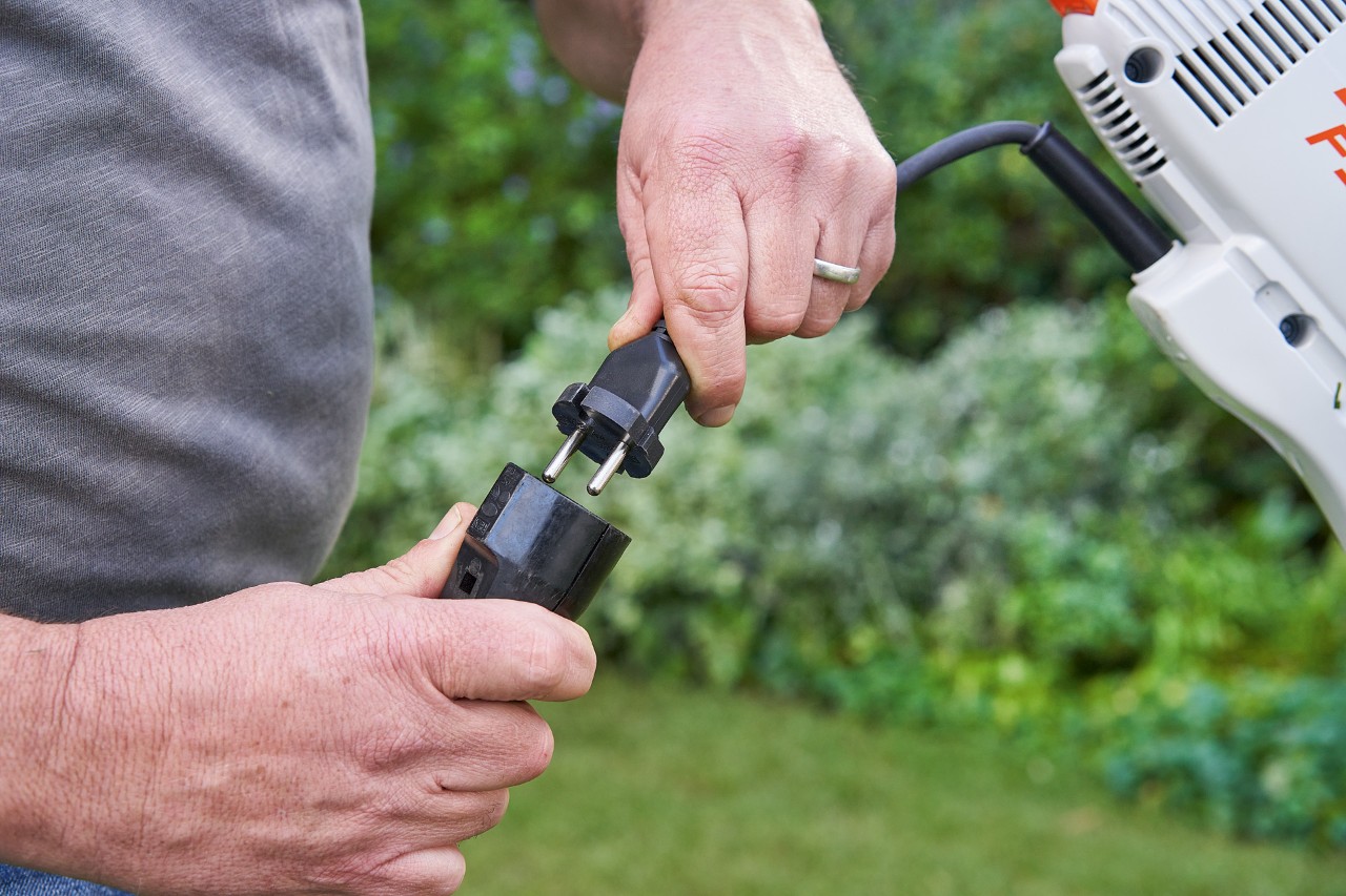 Un homme portant des gants de protection et appuyant sur le levier de commande de la débrousailleuse électrique STIHL&nbsp;FSE&nbsp;60 pour la démarrer