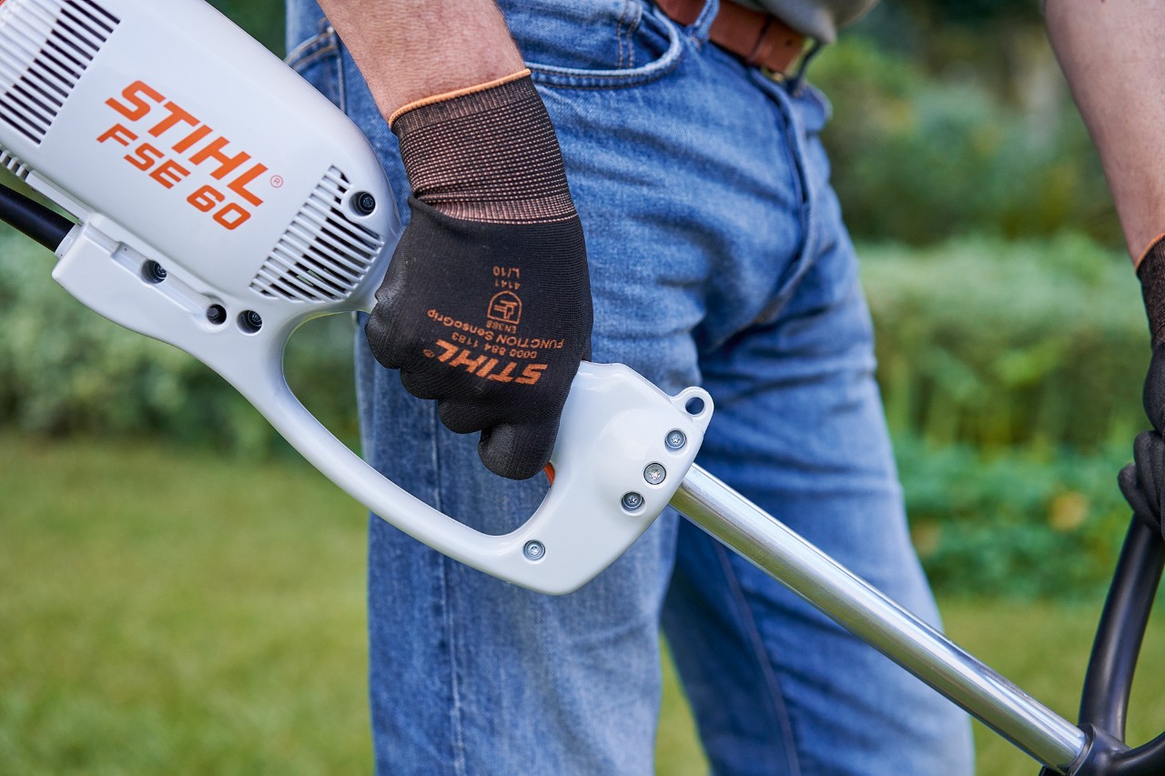 Un homme actionnant le commutateur de la poignée de commande de la débrousailleuse électrique STIHL&nbsp;FSE&nbsp;60