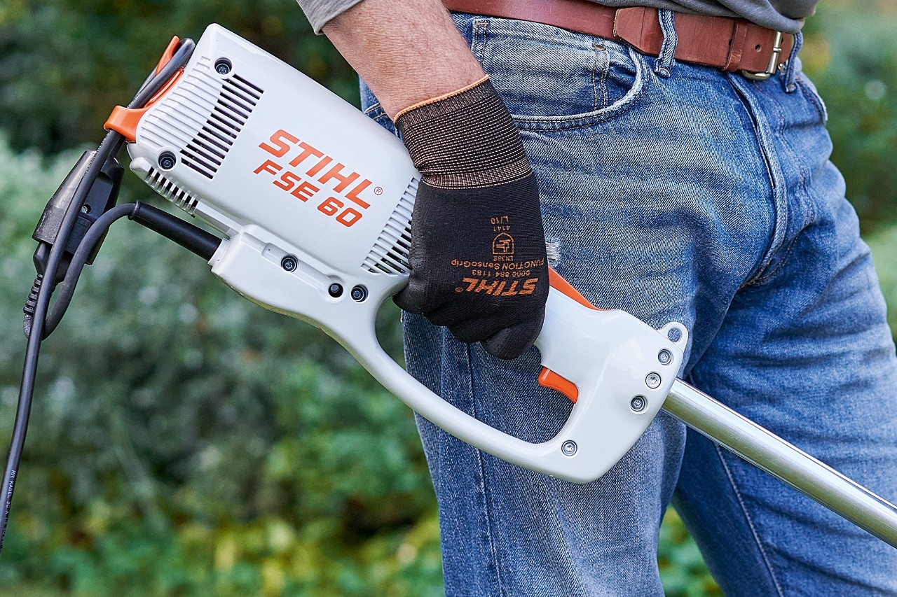 Un homme actionnant le commutateur pour éteindre la débrousailleuse électrique STIHL&nbsp;FSE&nbsp;60.