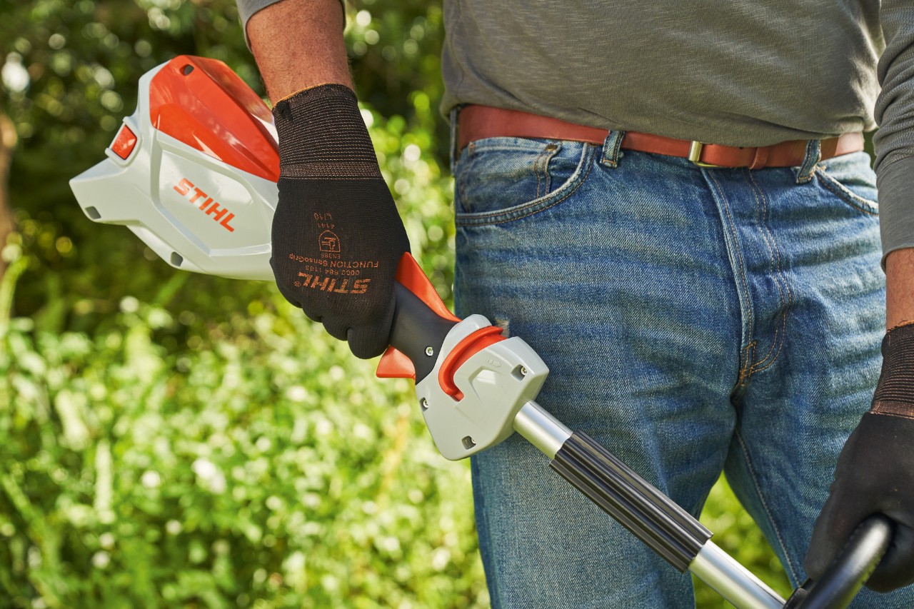 Un homme portant des gants de protection et relâchant le levier de commande de la débroussailleuse à batterie STIHL&nbsp;FSA&nbsp;60 pour l’arrêter
