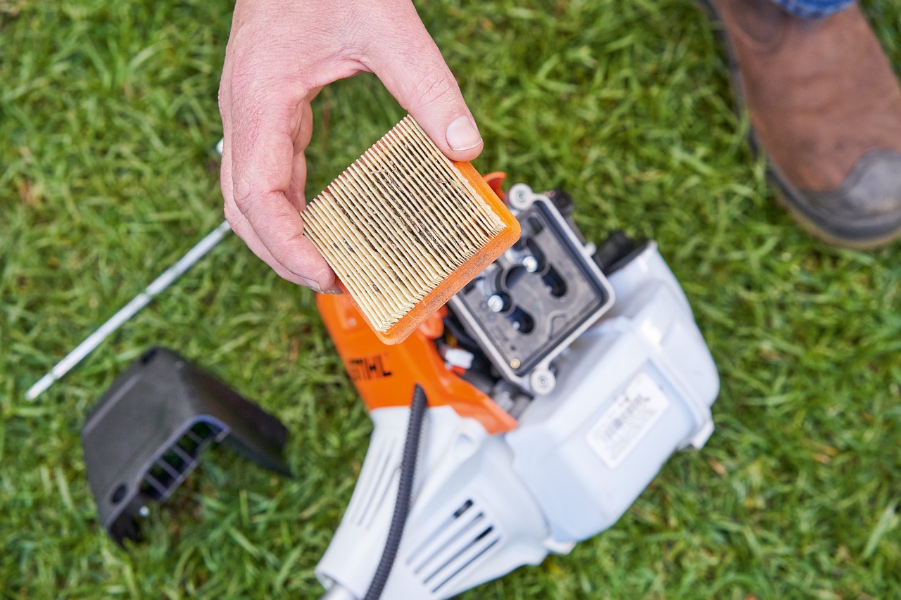 Une personne retirant le filtre à air d’une débroussailleuse STIHL pour le nettoyer 