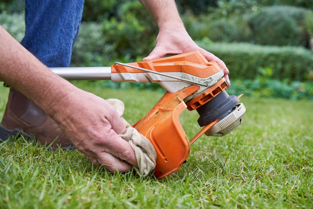 Une personne nettoyant la protection d’une débroussailleuse STIHL avec un chiffon humide