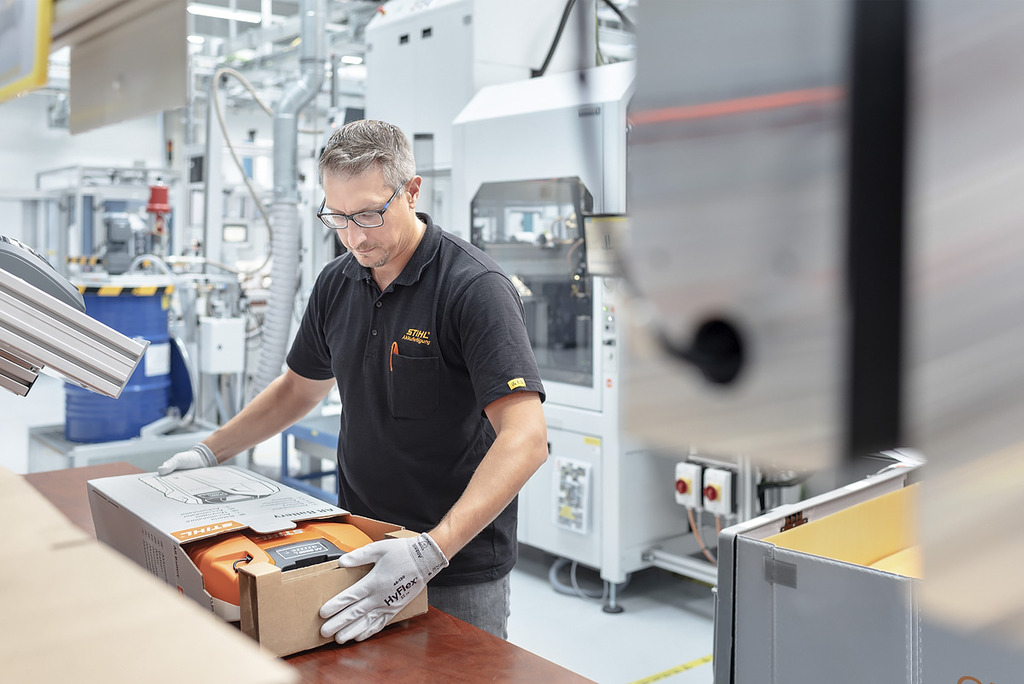 Un employé de la production de batteries emballe un appareil à batterie STIHL dans un carton 