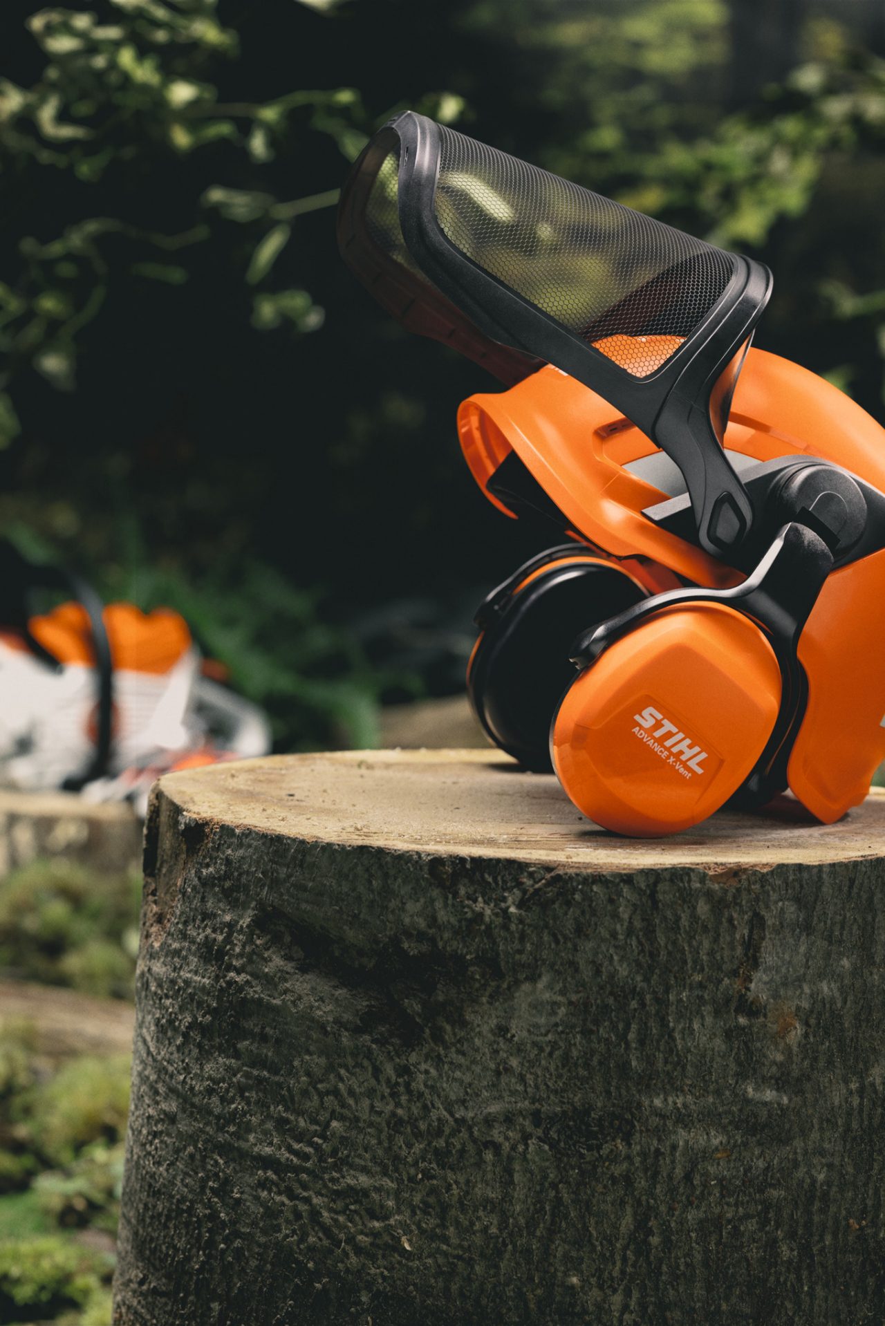 Gros plan du casque STIHL Advance X-Vent ProCom fixé sur un tronc d'arbre