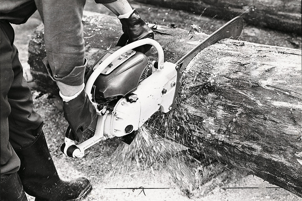 Vieille photo en noir et blanc d’une personne coupant un arbre avec une tronçonneuse STIHL Contra 
