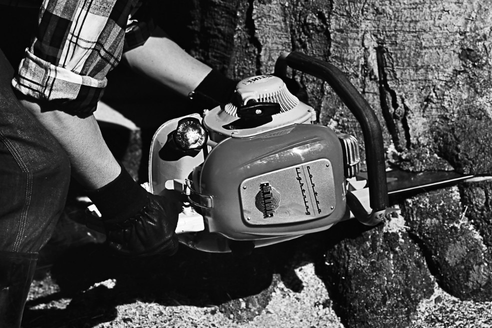 Vieille photo noir et blanc en gros plan montrant une personne en train d’abattre un arbre à l’aide d’une tronçonneuse STIHL Contra