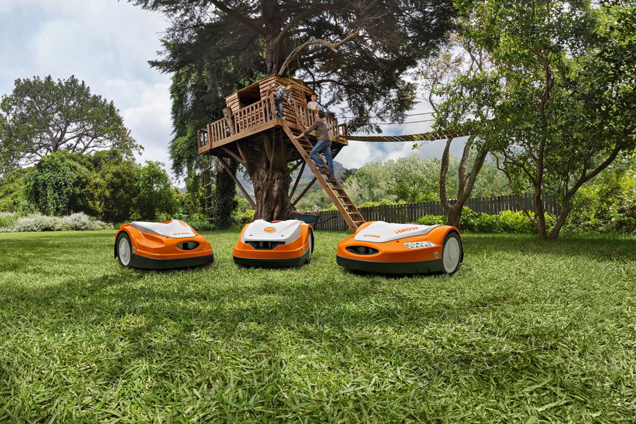 Gamme de tondeuses robots STIHL iMOW® sur une pelouse verte dans le jardin