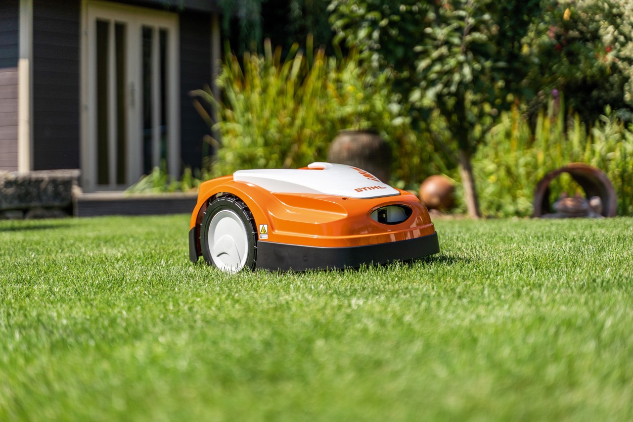 Tondeuse robot STIHL iMOW® RMI 422 sur une pelouse verte devant une maison